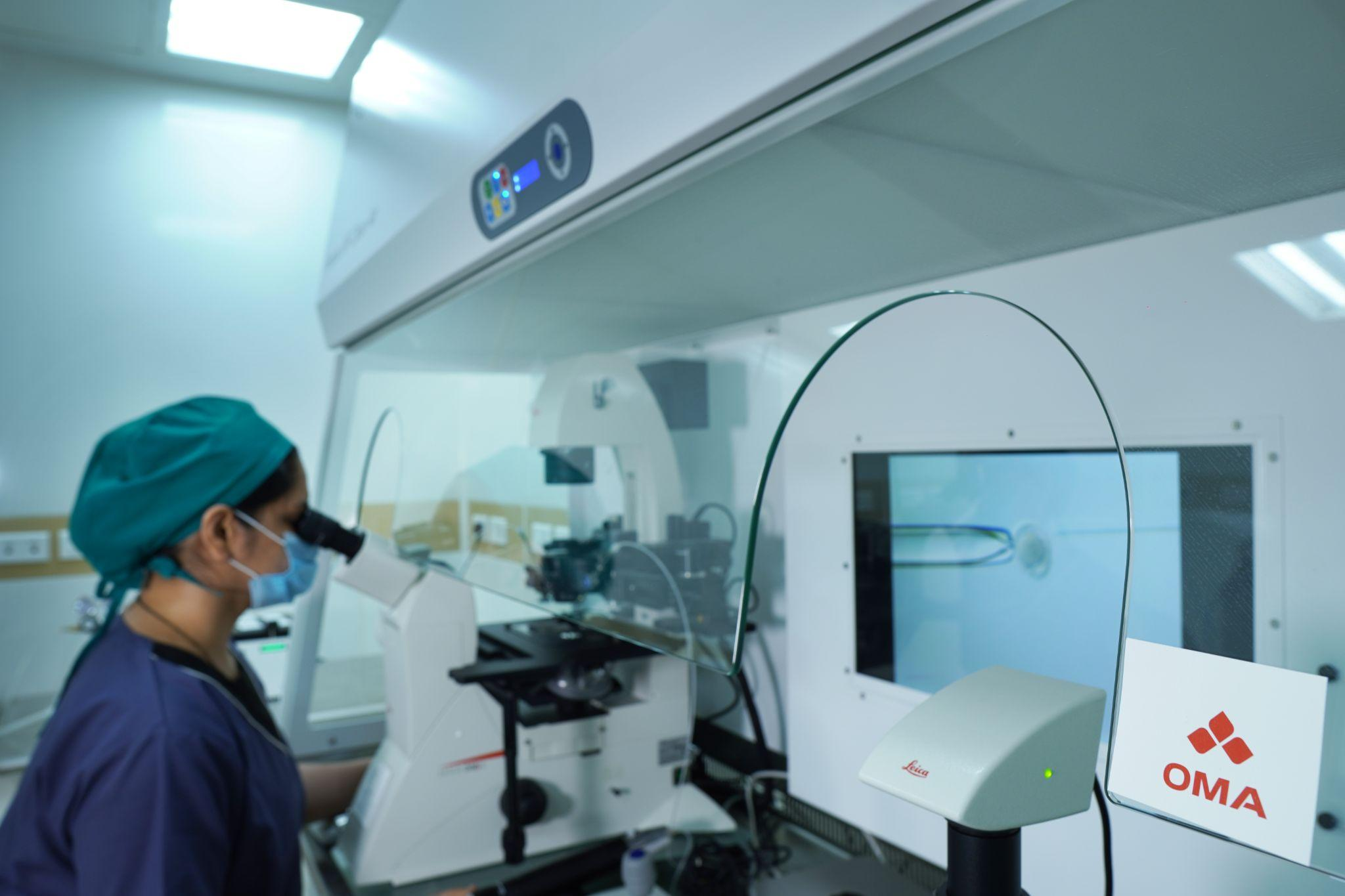 Picture1(82) Medical professional wearing a green cap and mask operating a microscope in a clean laboratory.